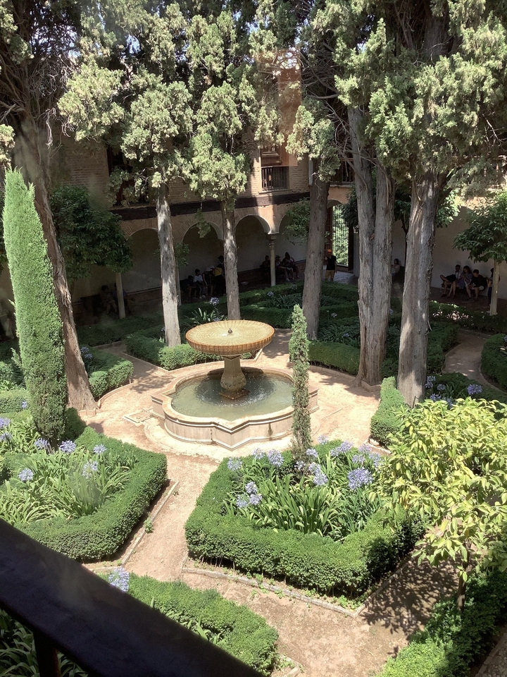 Jardin de cour avec une fontaine centrale entourée d'arbres.