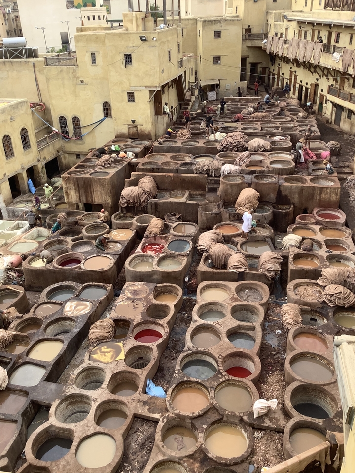 Tannerie traditionnelle avec de nombreuses cuves colorées et des personnes qui travaillent.