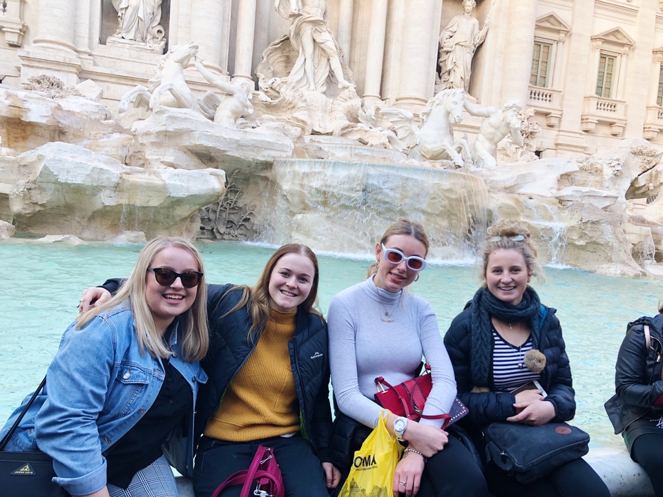 Groupe de personnes posant devant une fontaine célèbre.