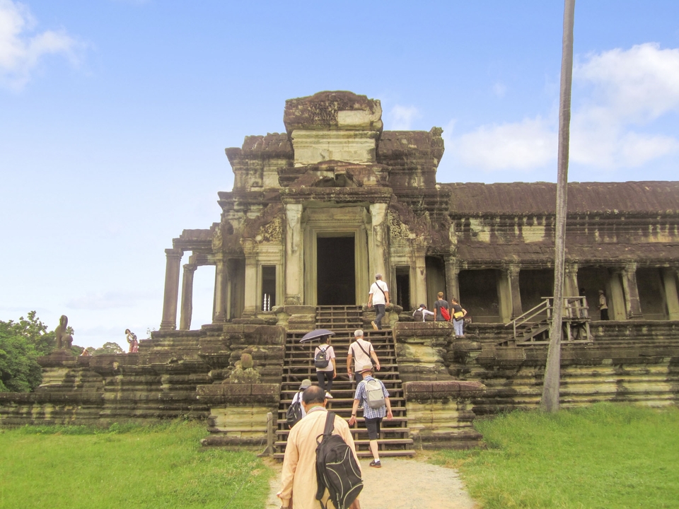 Des touristes gravissant les marches vers un temple ancien.