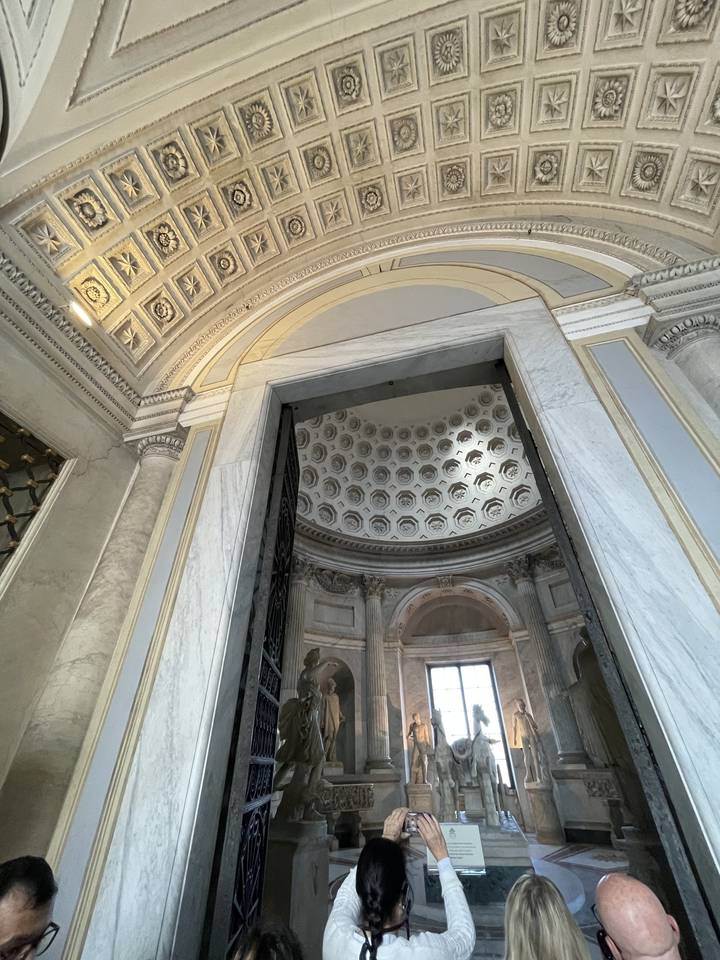 Intérieur d'un bâtiment historique avec des sculptures et des visiteurs.