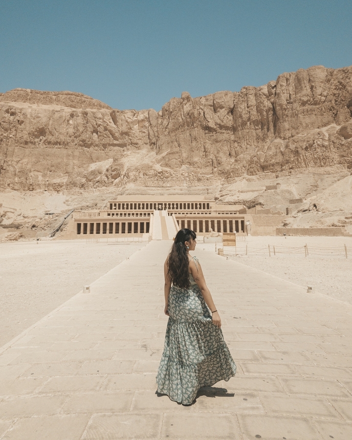 Une femme debout devant le temple d'Hatchepsout.