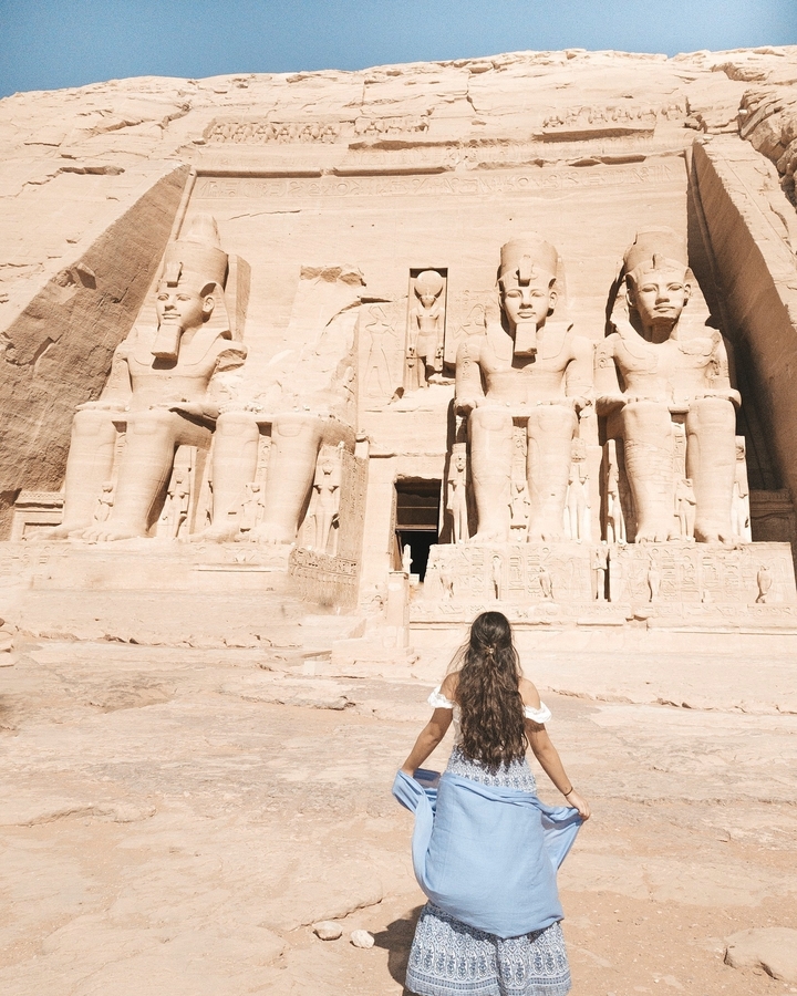Une femme assise devant le Grand Temple d'Abou Simbel.