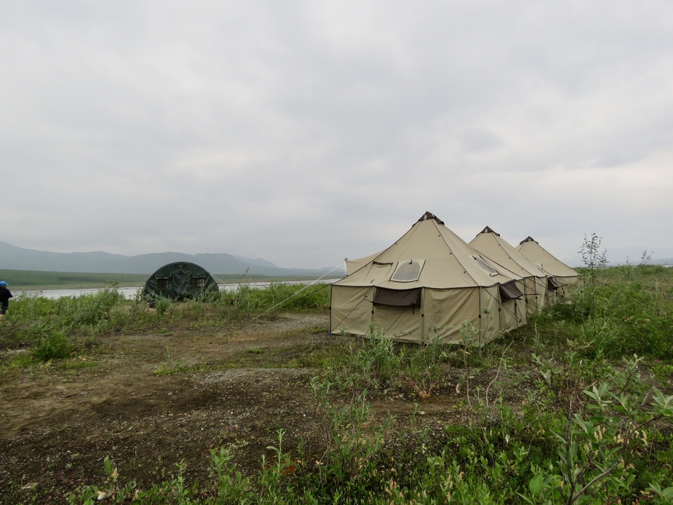 Tentes dressées dans un paysage désolé avec un ciel nuageux.