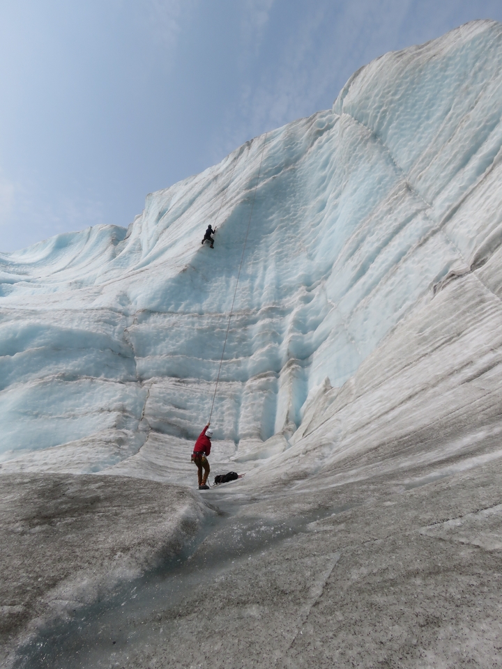 Deux personnes escaladent un grand glacier.