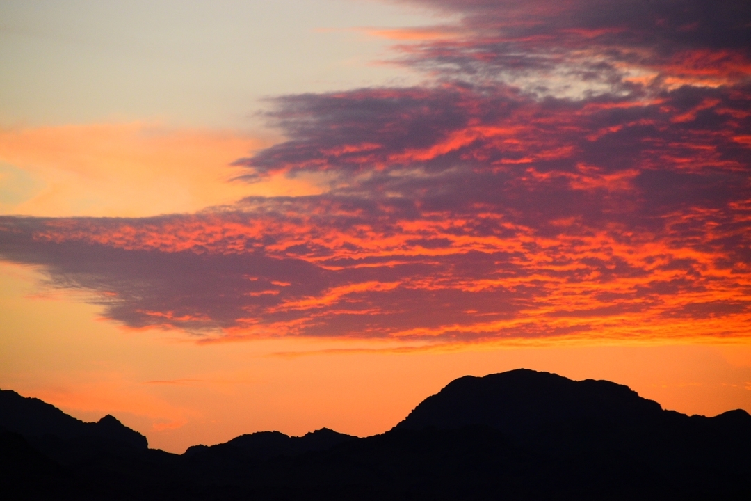Coucher de soleil éclatant avec des montagnes en silhouette.