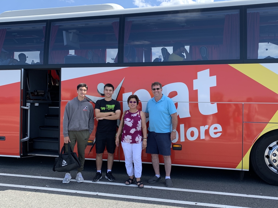 Groupe de personnes debout devant un autocar de tourisme.