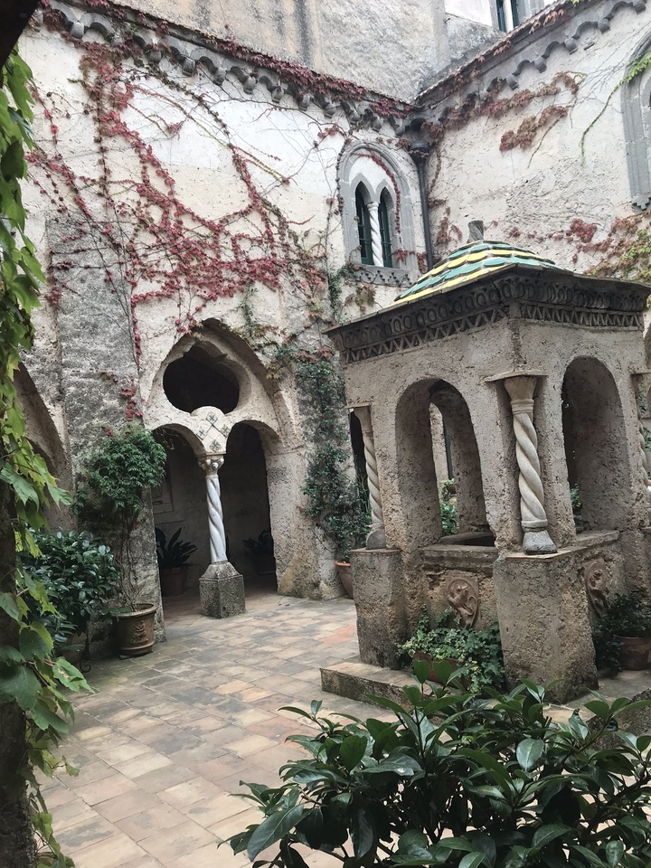 Ancienne cour pavée avec arcs et lierre grimpant.