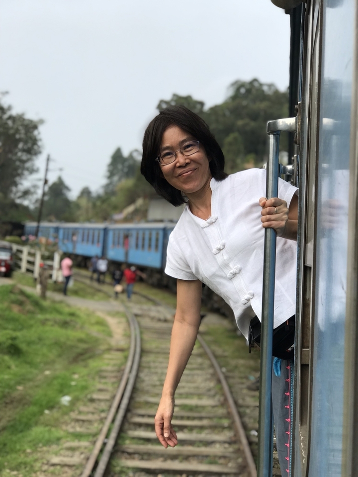 Personne se penchant par la fenêtre d'un train bleu.