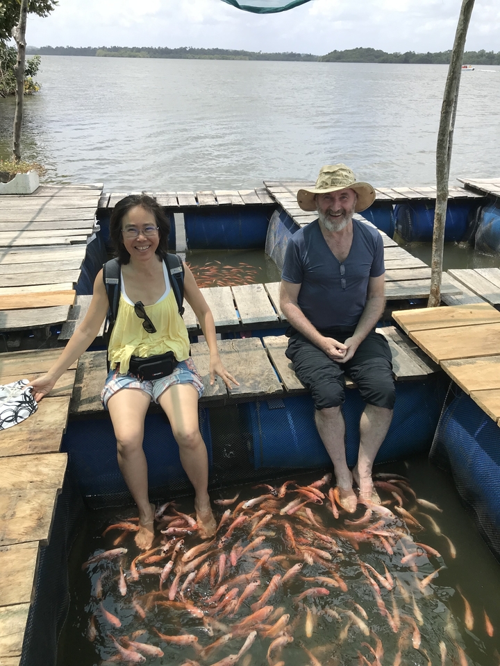 Deux personnes assises sur une structure avec des poissons en dessous.