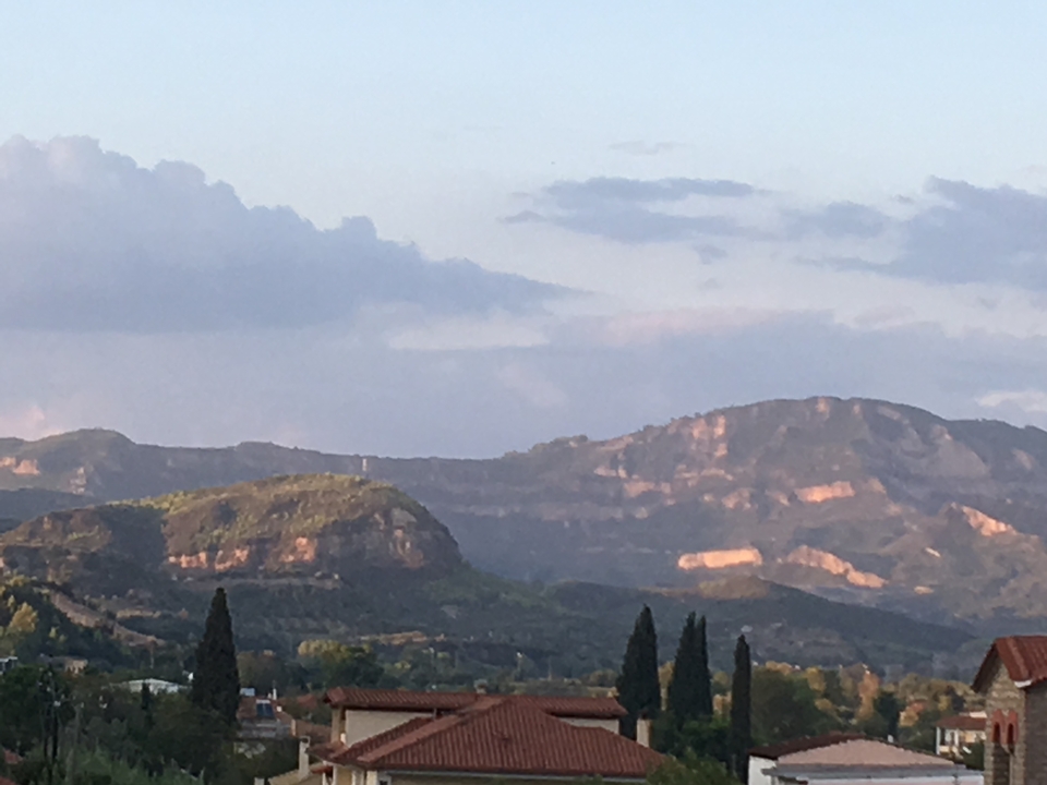 Paysage montagneux avec des arbres et un ciel nuageux.