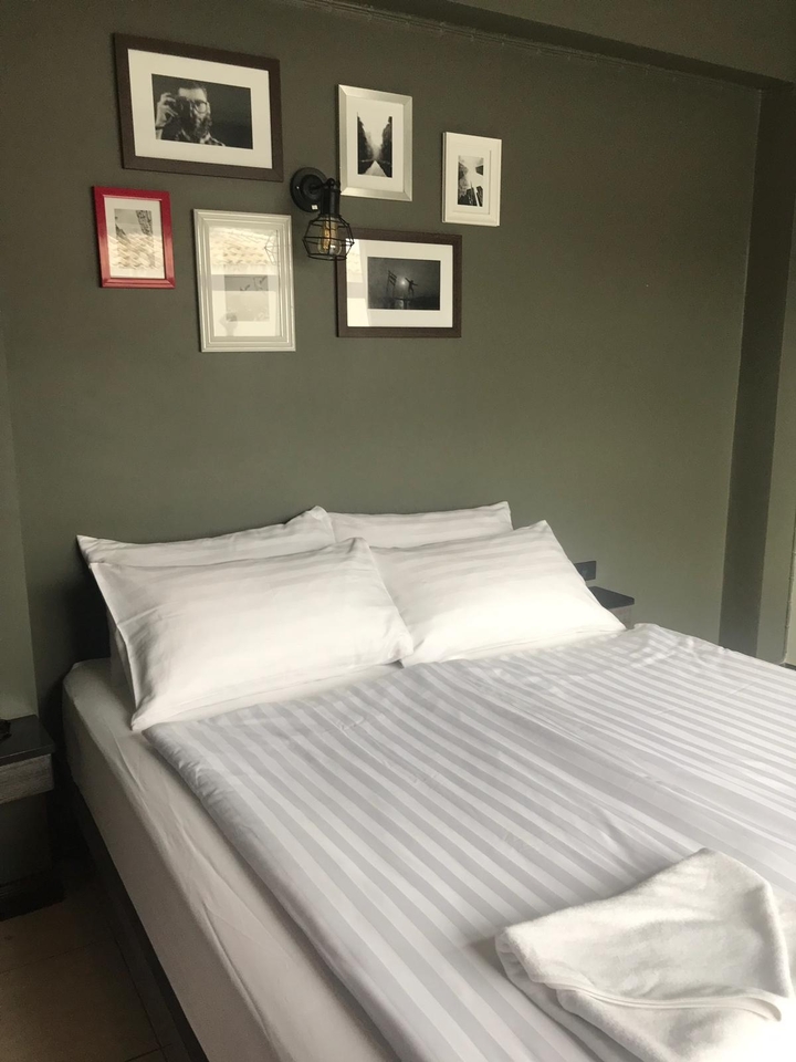 Einfaches Schlafzimmer mit gemachtem Bett und Bildern an der Wand.