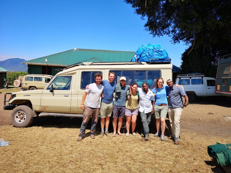 Gruppe von Menschen, die vor einem Safari-Fahrzeug posieren.