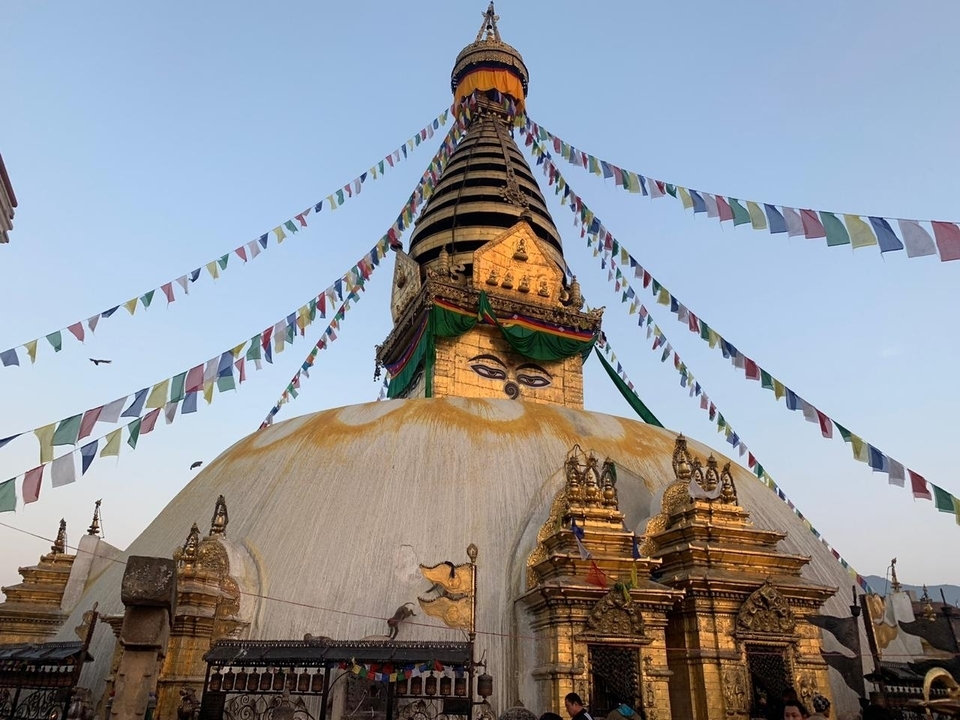 Stupa bouddhiste avec des drapeaux de prière colorés contre un ciel dégagé.