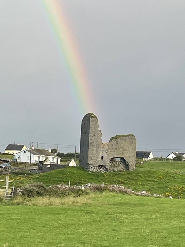 Ruines d'un ancien bâtiment en pierre avec un arc-en-ciel dans le ciel.