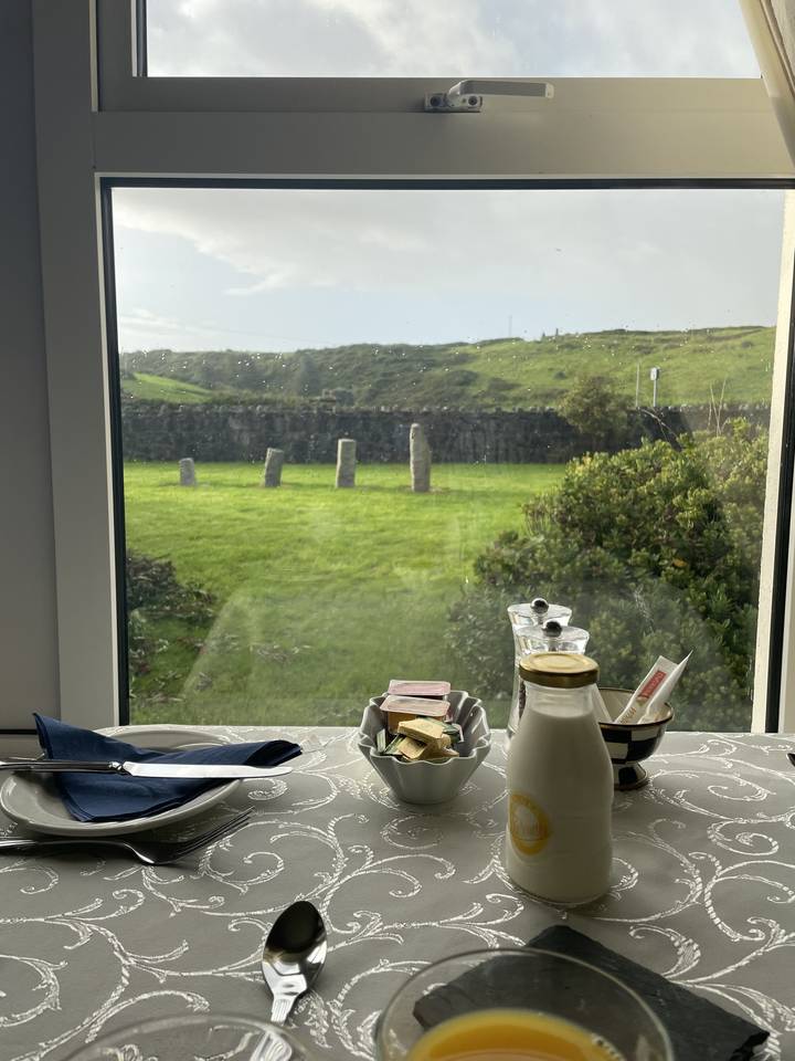 Table à manger près d'une fenêtre avec une vue panoramique sur des champs verts.