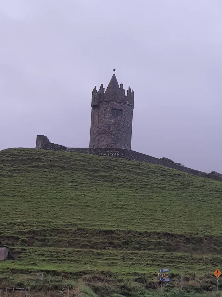 Une tour dans un paysage herbeux sous un ciel nuageux.