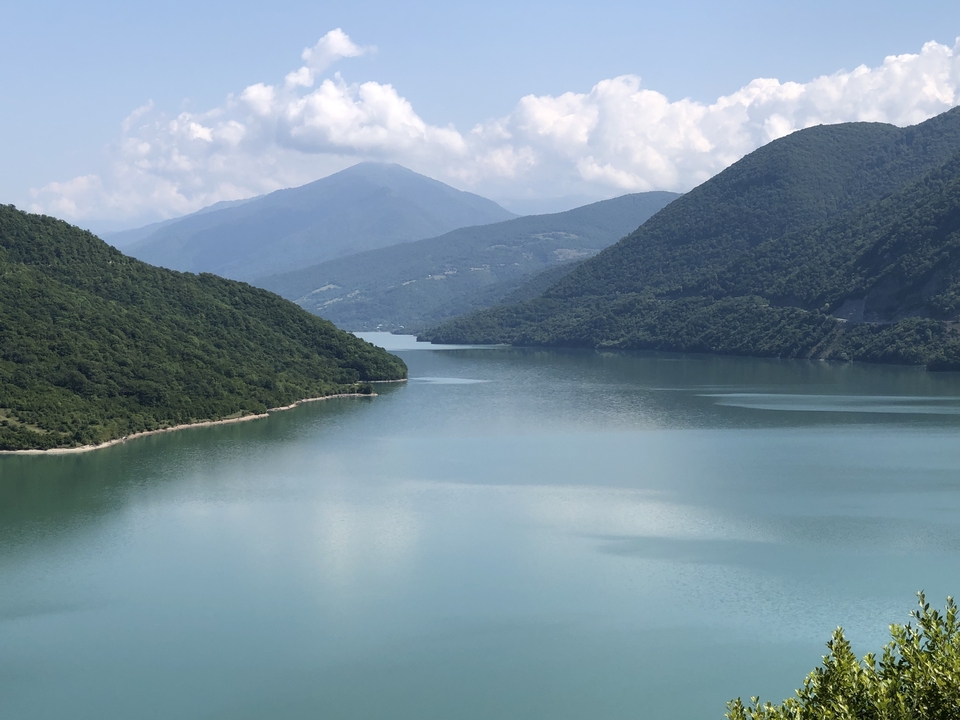 Large rivière avec toile de fond montagneuse sous un ciel dégagé.