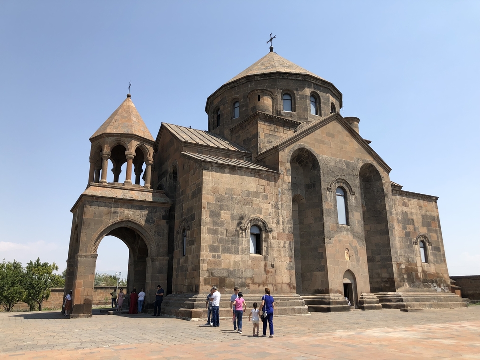 Une église de pierre avec un groupe de personnes à l'extérieur.