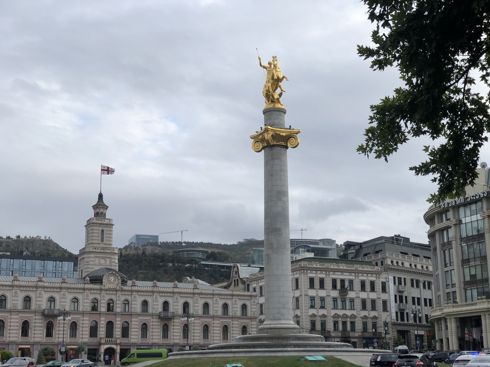 Colonne monumentale avec une statue au sommet sur une place de ville.