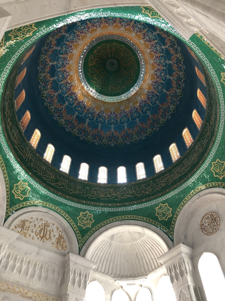 Intérieur de mosquée richement décoré avec dôme coloré.