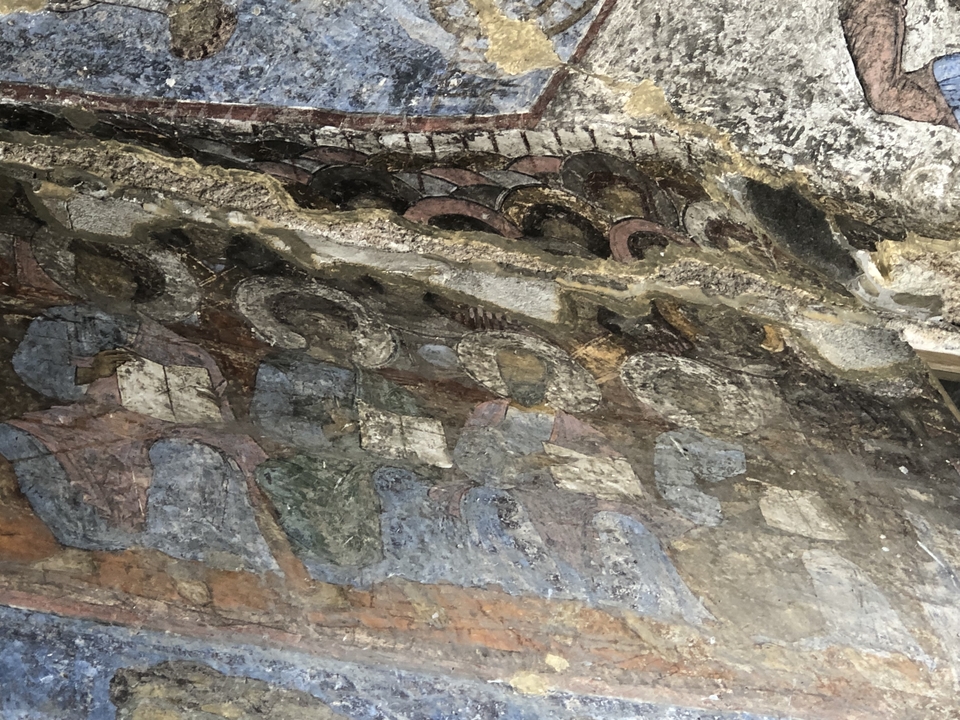 Fresques anciennes sur un mur de pierre.