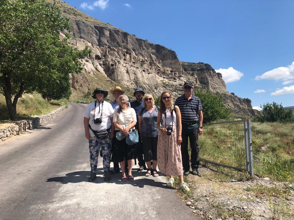 Des touristes qui posent devant d'anciennes grottes rocheuses.