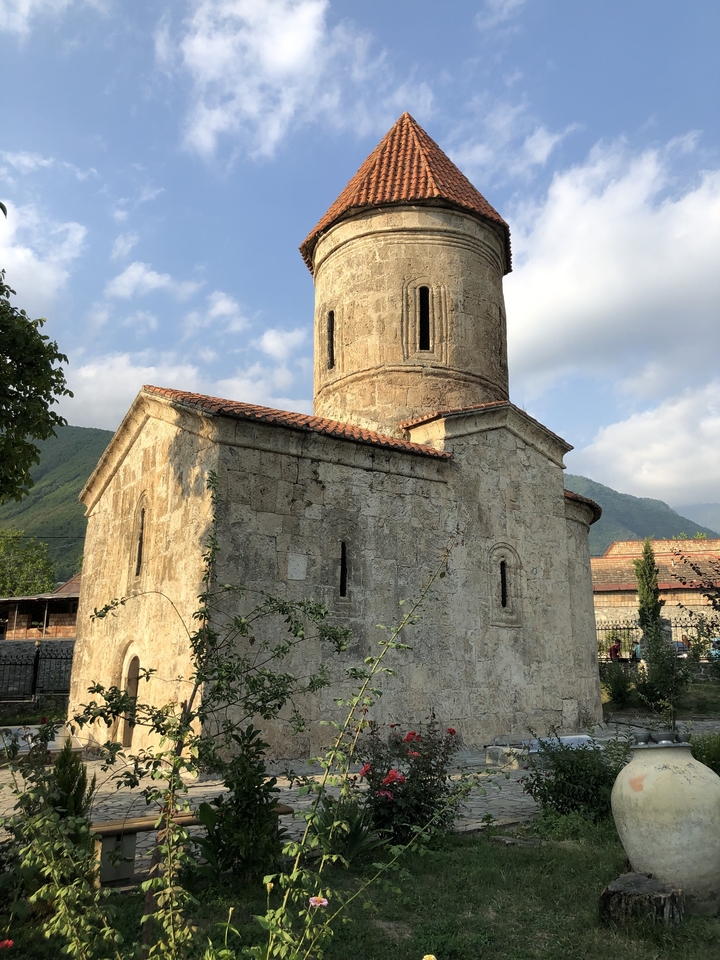 Une petite église en pierre avec une tour ronde dans un cadre montagneux.