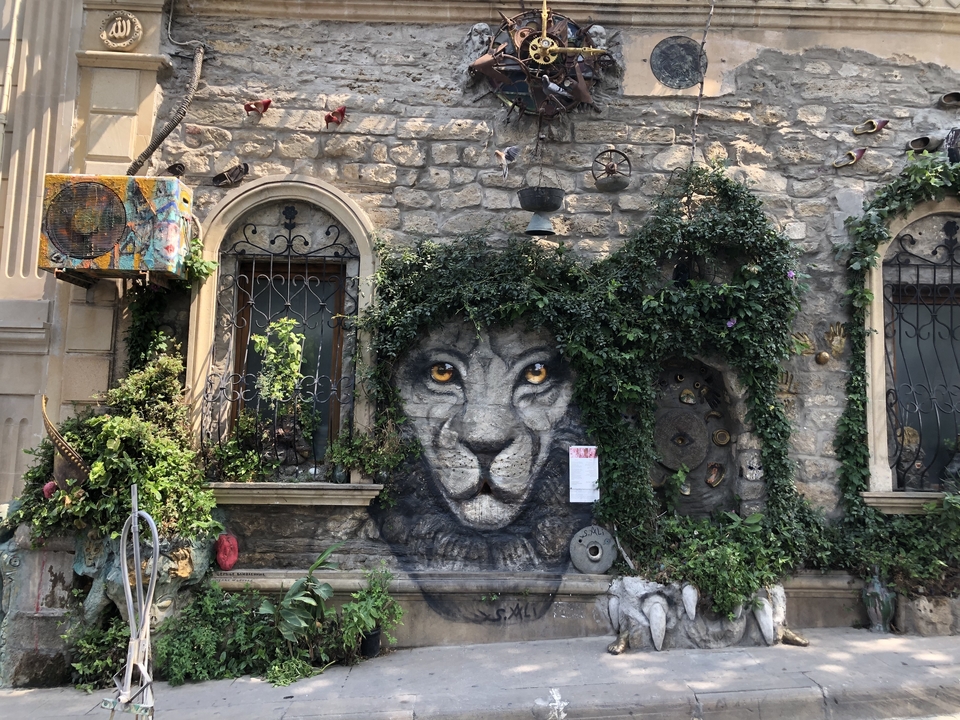 Façade de bâtiment avec feuillage vert et peinture murale de lion.