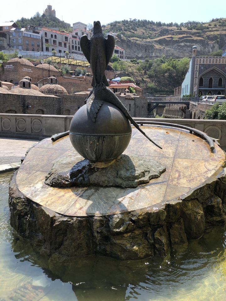 Fontaine avec une sculpture d'un oiseau perché sur un globe.