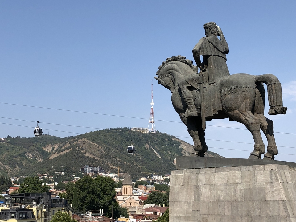 Statue équestre dominant une montagne avec téléphériques.