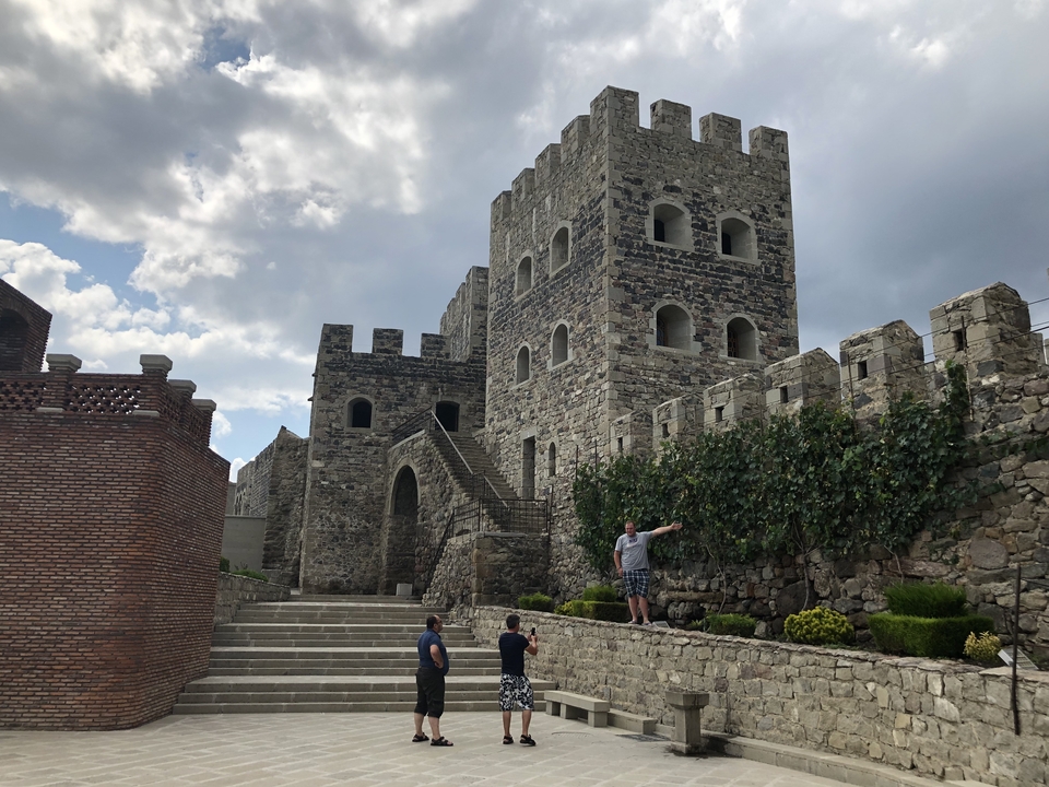Des gens explorant un château de pierre avec des escaliers.