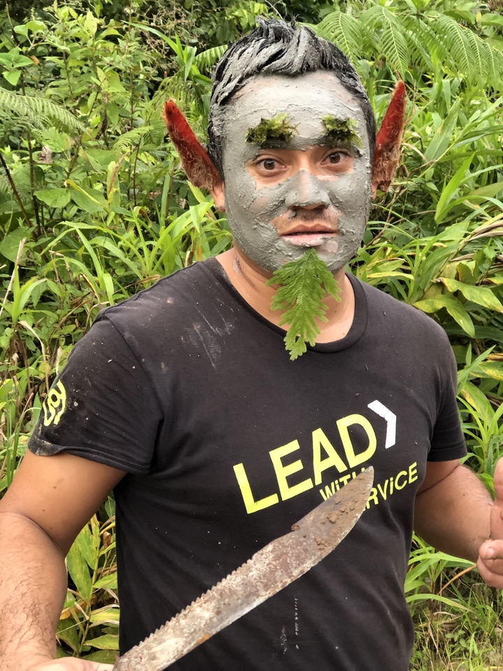 Personne avec le visage peint d'argile et une feuille attachée.