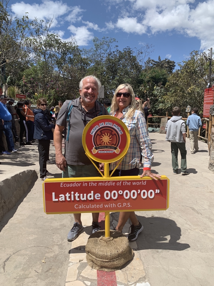 Des personnes qui posent avec le panneau de l'Équateur à un point touristique.