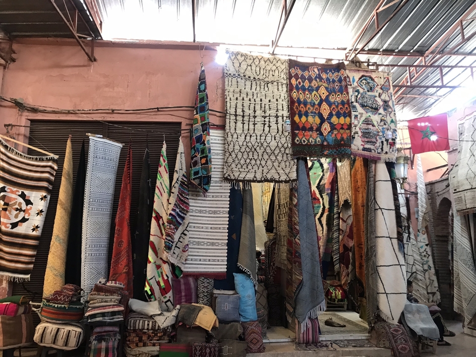 Variété de textiles et de tapis exposés dans un marché.