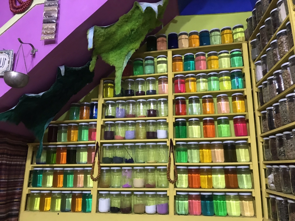 Des bocaux colorés d'épices sur une étagère dans un marché.