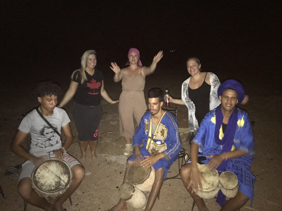 Des gens rassemblés qui jouent du tambour dans le désert la nuit.