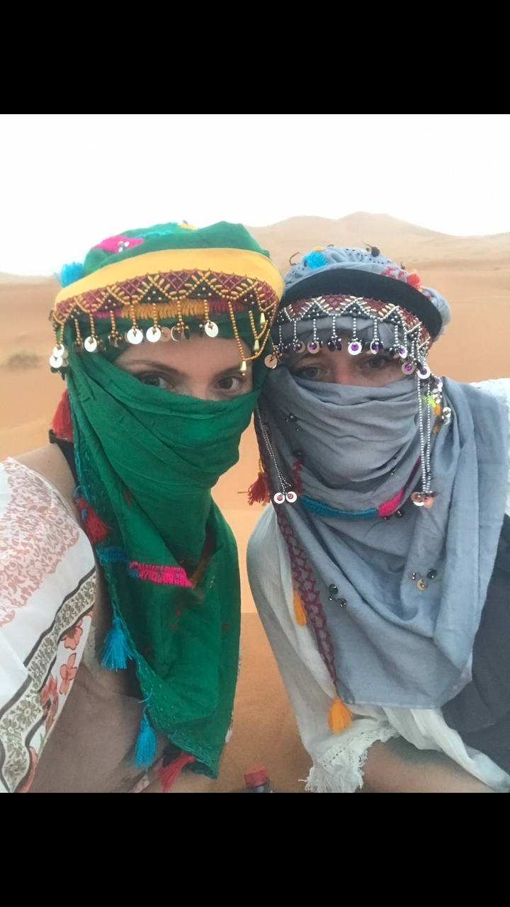 Deux personnes portant des foulards traditionnels dans un désert.
