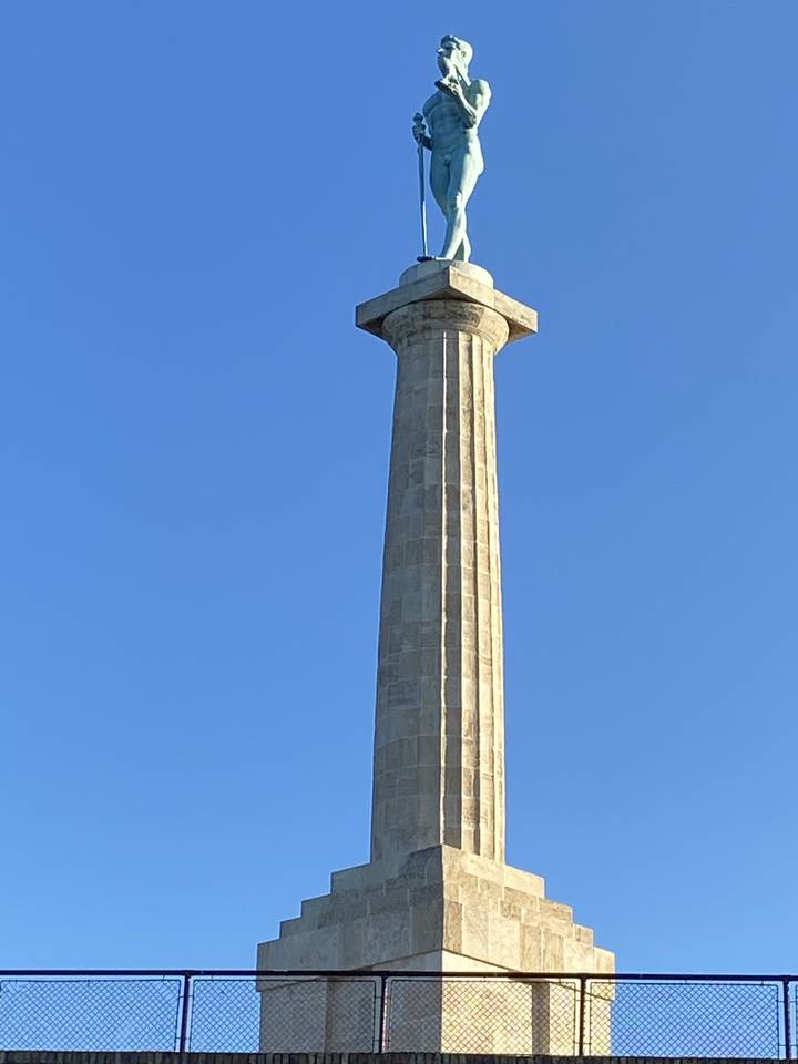 Hohe Steinsäule mit einer Statue oben drauf.