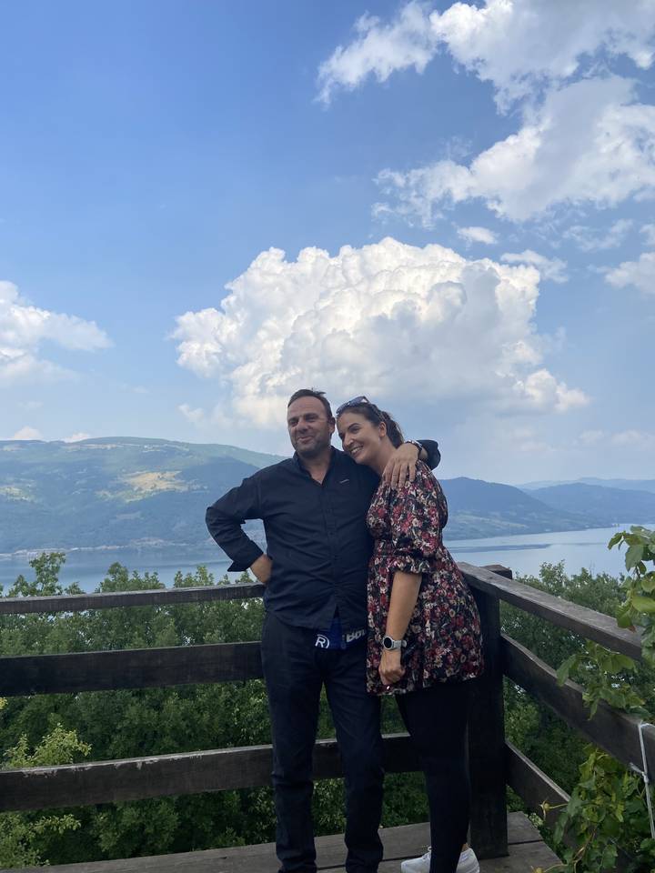 Paar steht an einem Aussichtspunkt mit einer malerischen Landschaft.