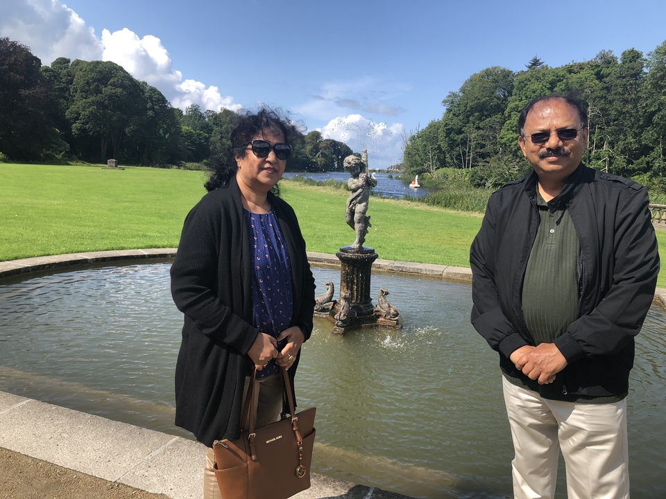 Deux personnes posant devant une fontaine et un lac.