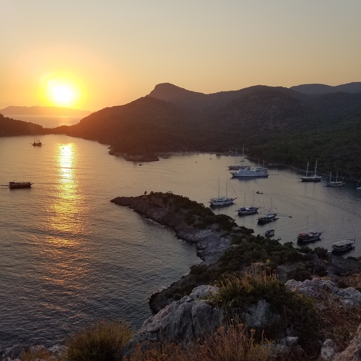 Vue du coucher de soleil sur une baie avec plusieurs bateaux.