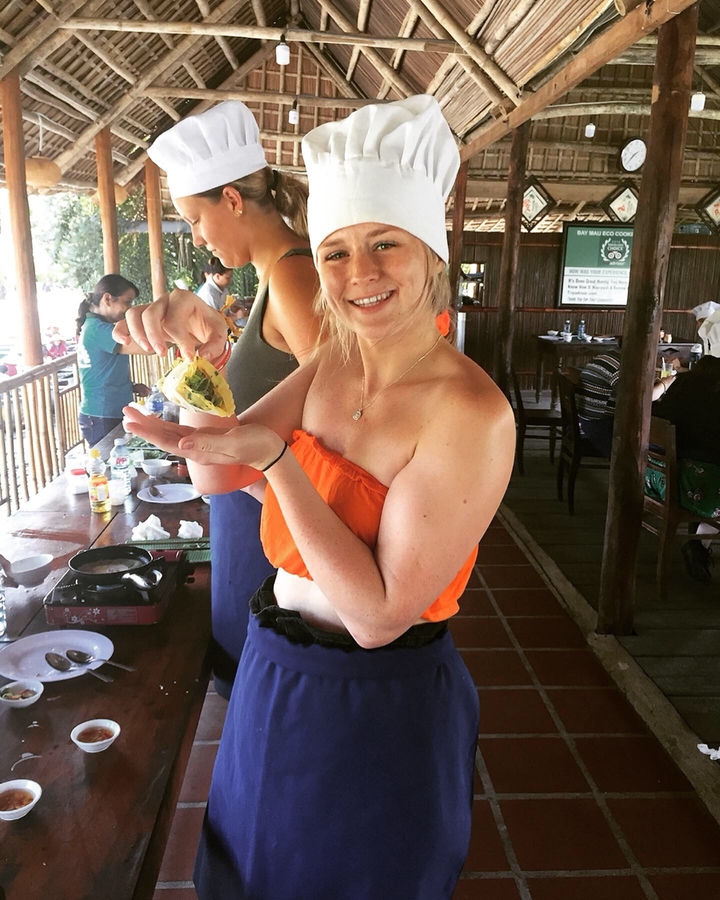 Una mujer presentando un plato colorido en un entorno culinario.