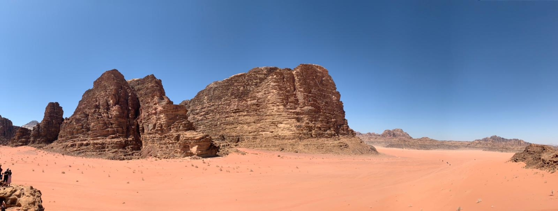 A large rock formation in the desert under a clear blue sky.