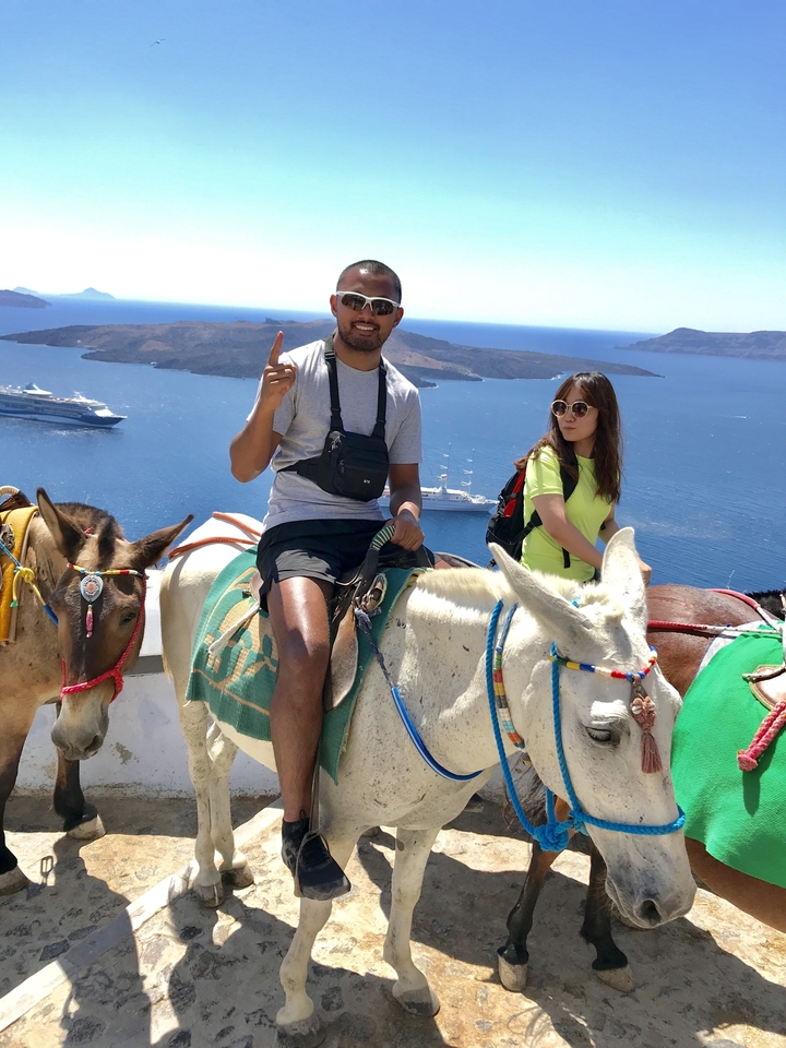 People riding donkeys with views of the sea and islands in the background.