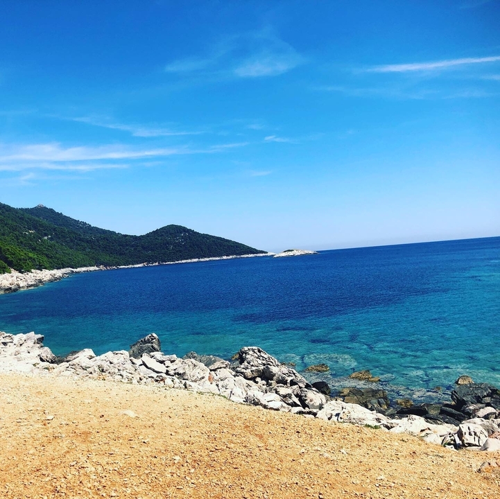 Mer bleue claire avec des collines rocheuses en arrière-plan.