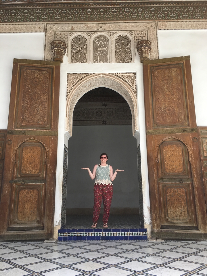 Une femme se tenant dans une grande porte ornée.