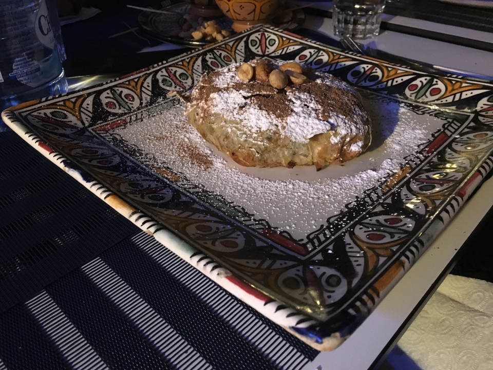 Un plat dressé de cuisine marocaine garni de noix et de sucre en poudre.