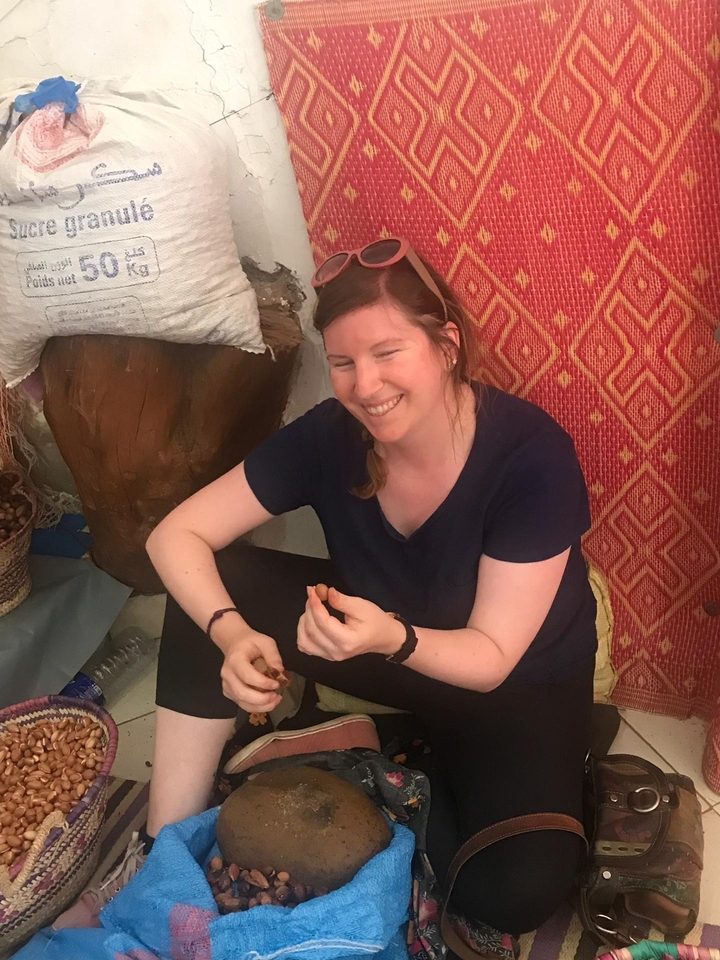 Une femme souriante assise à l'intérieur d'un magasin.