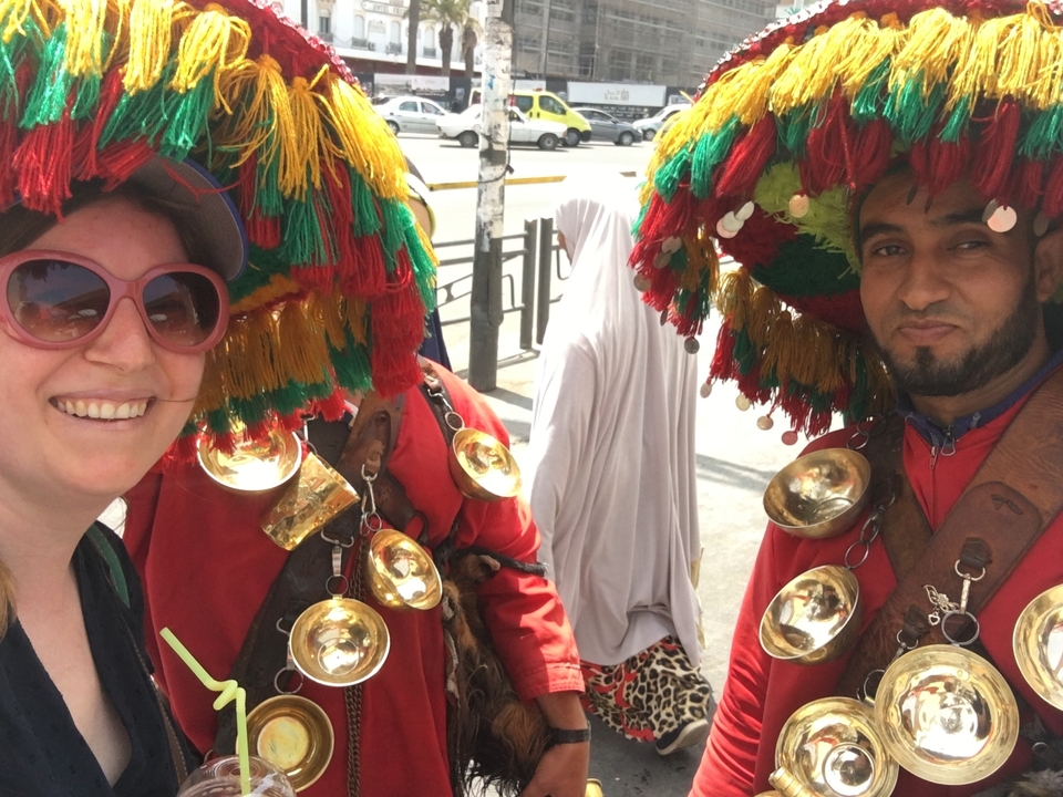 Une femme posant avec deux hommes portant des tenues traditionnelles marocaines avec des couvre-chefs.